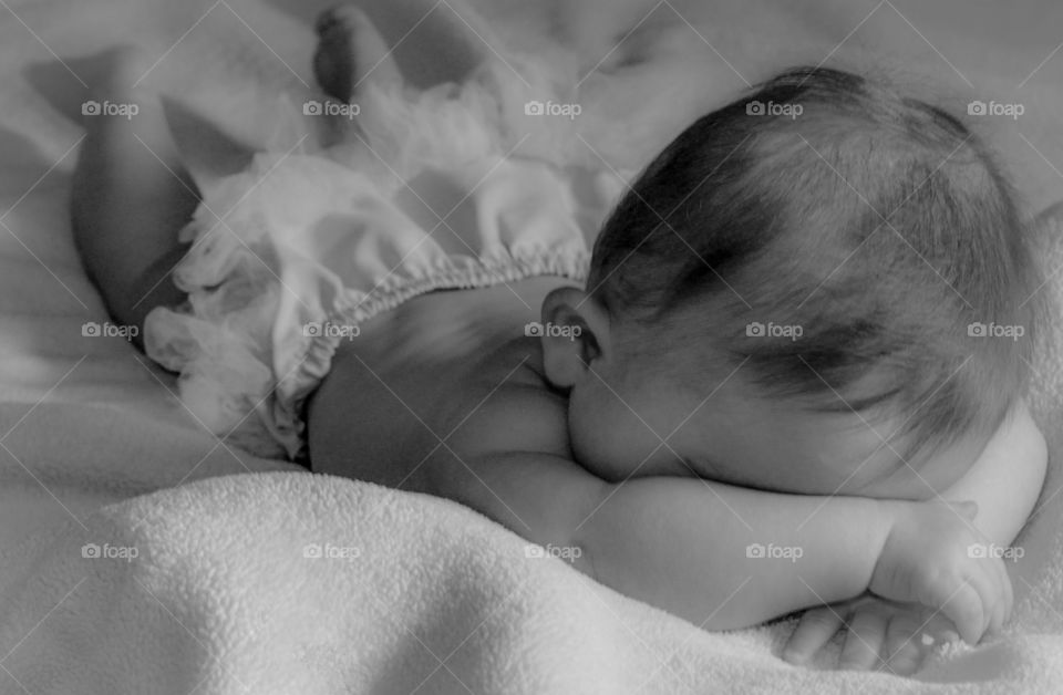 Baby girl hiding her face. Baby girl playing on her stomach hiding her face in black-and-white