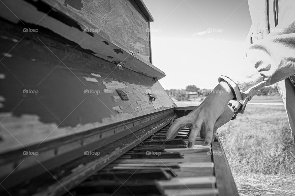 The girl plays the piano by the sea in the open air.