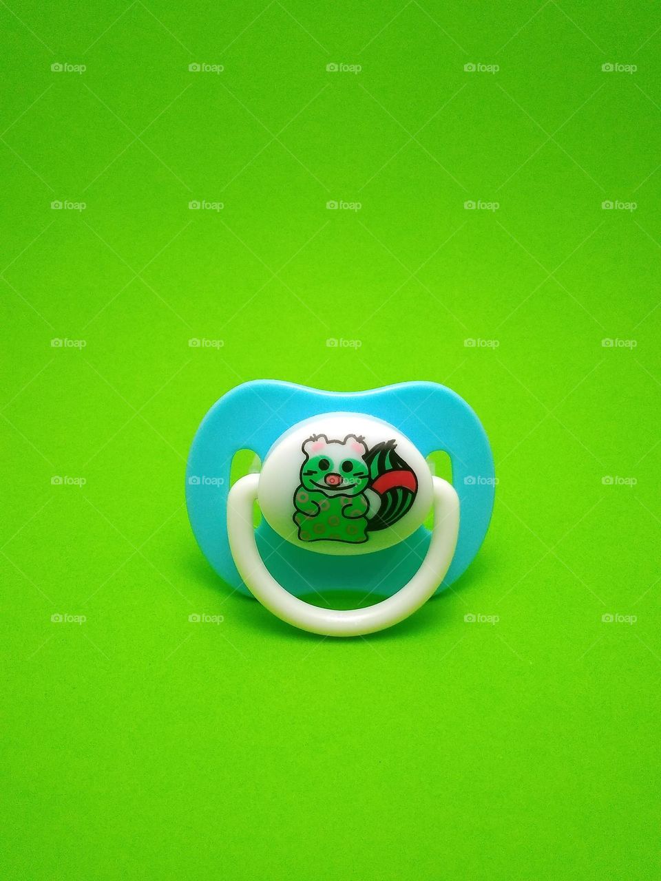 baby pacifier, a tool to calm the baby as a substitute for the mother's nipple on green background.