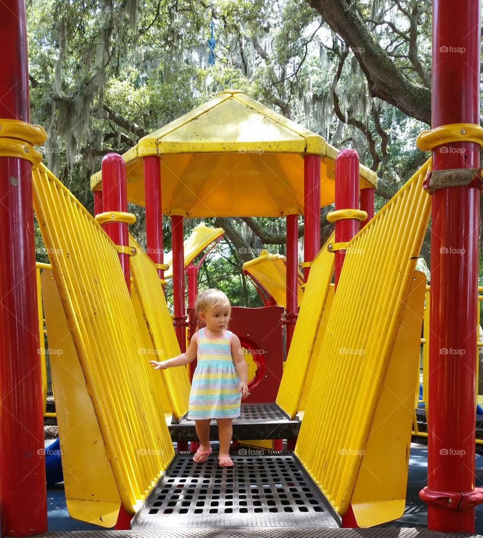 Toddler girl standing on playground bridge