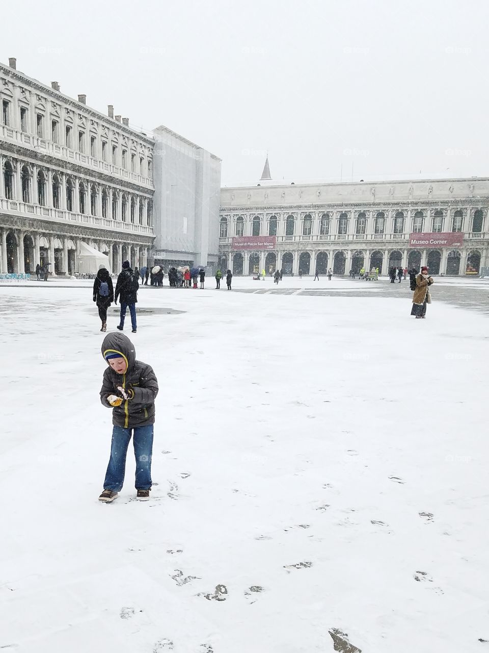 Boy in St Mark's square on a snowy day in Venice