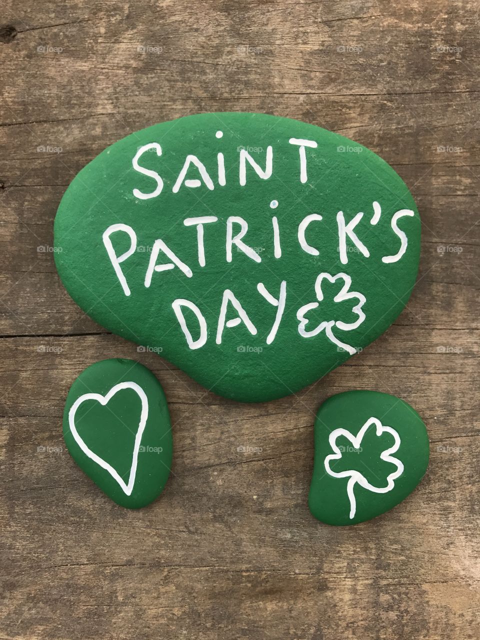 Saint Patrick's Day message with green painted stones over a wooden board