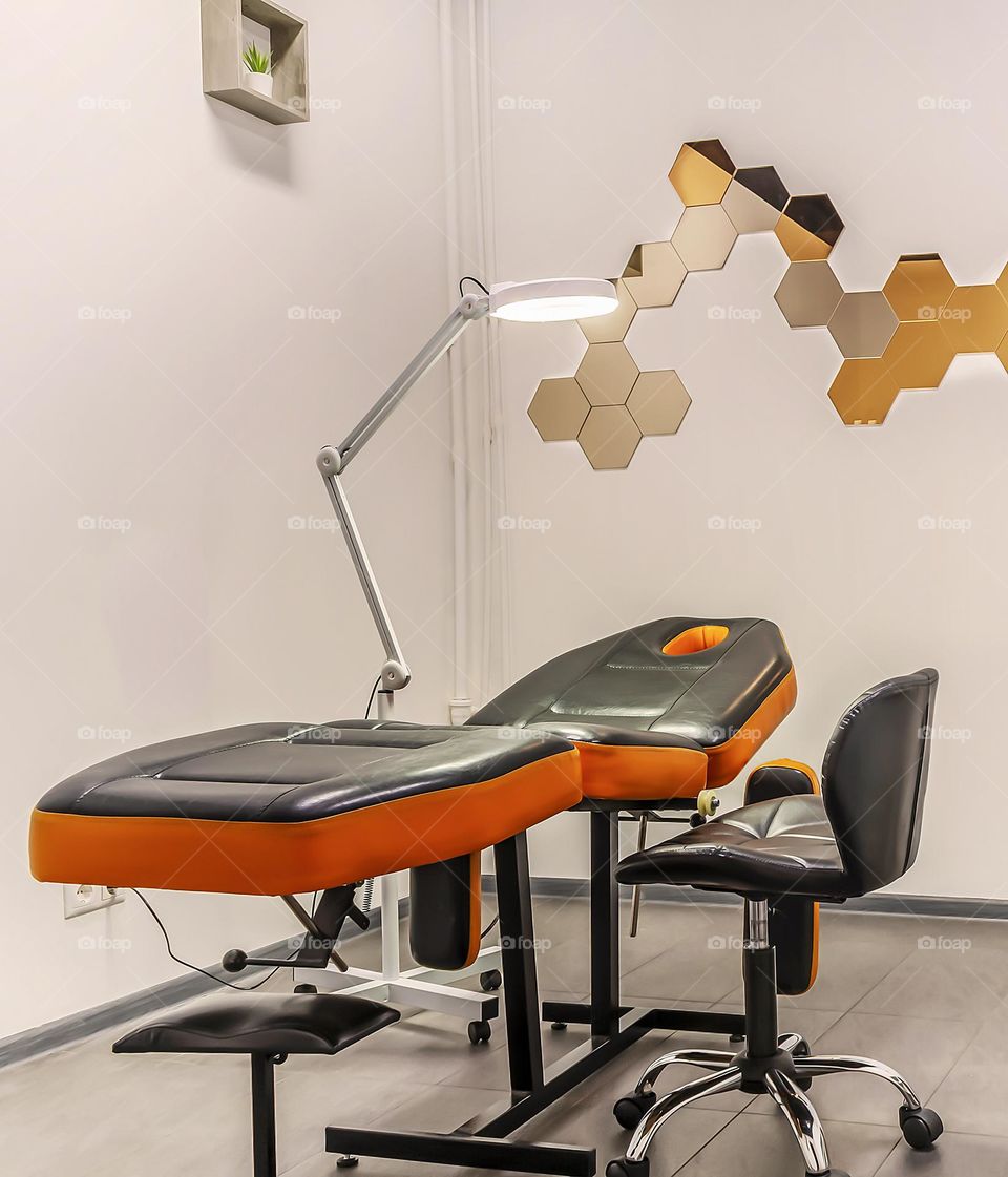 Interior of a modern cosmetology room in a beauty salon. Cosmetologist's workplace with a comfortable couch, armchair and professional lighting. Contemporary treatment room. Horizontal orientation