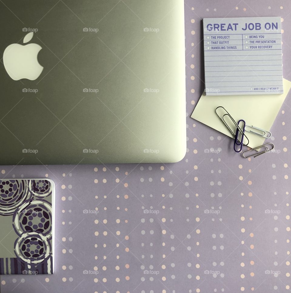 Flat lay from above of office supplies and an Apple computer in a purple and mauve and grey theme