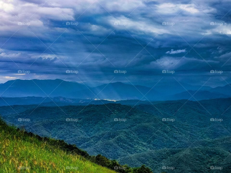 Looking towards Laos from Thailand, a narrow sunburst illuminates the valley below.