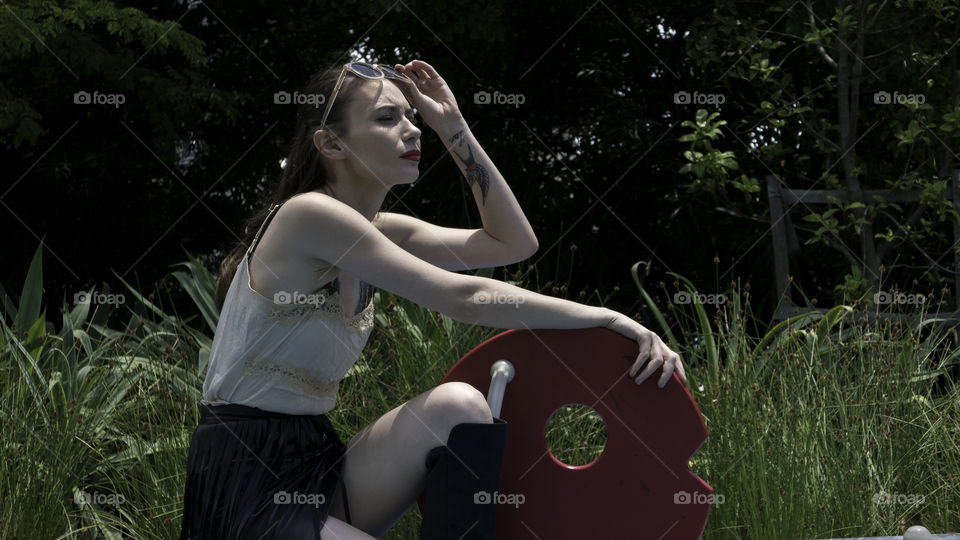 Beautiful woman crouching near object in grass
