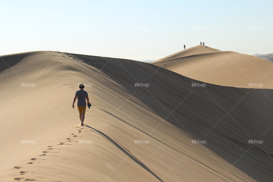 Rear view of man walking on sand