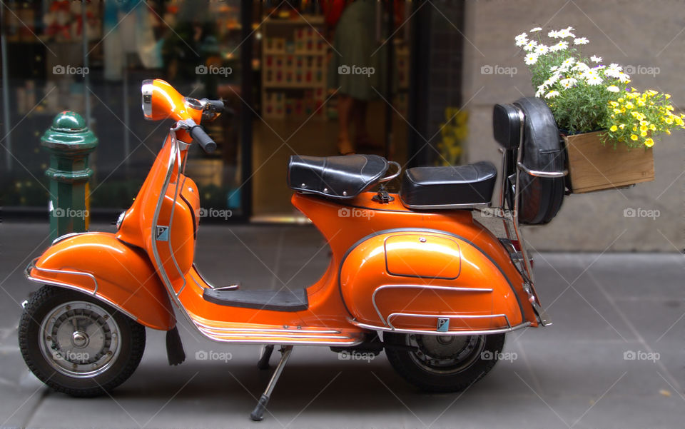 orange Vespa on the streets with flower's