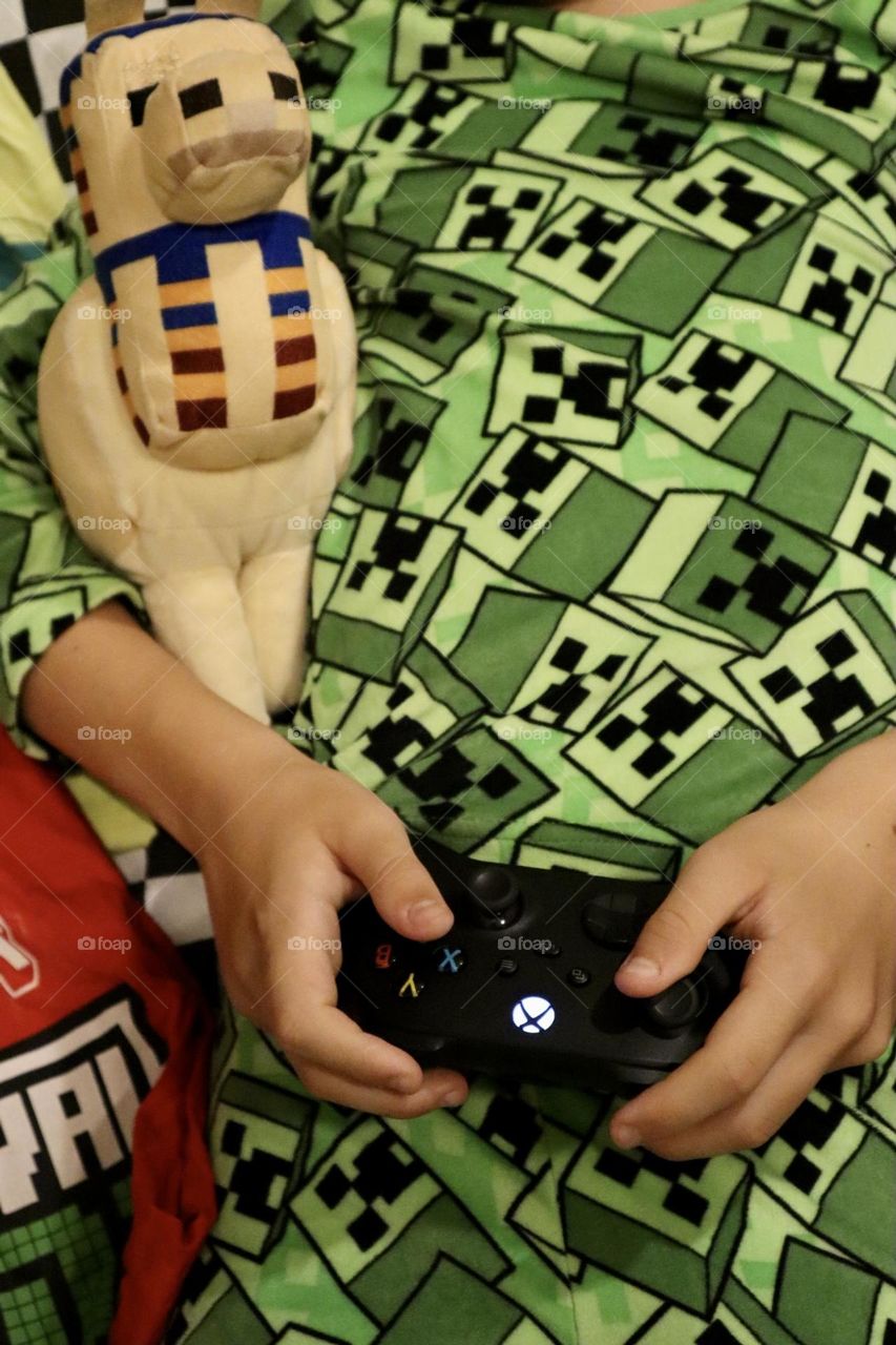 Xbox controller holding by kid wearing Minecraft pyjama and hugging Minecraft Llama 