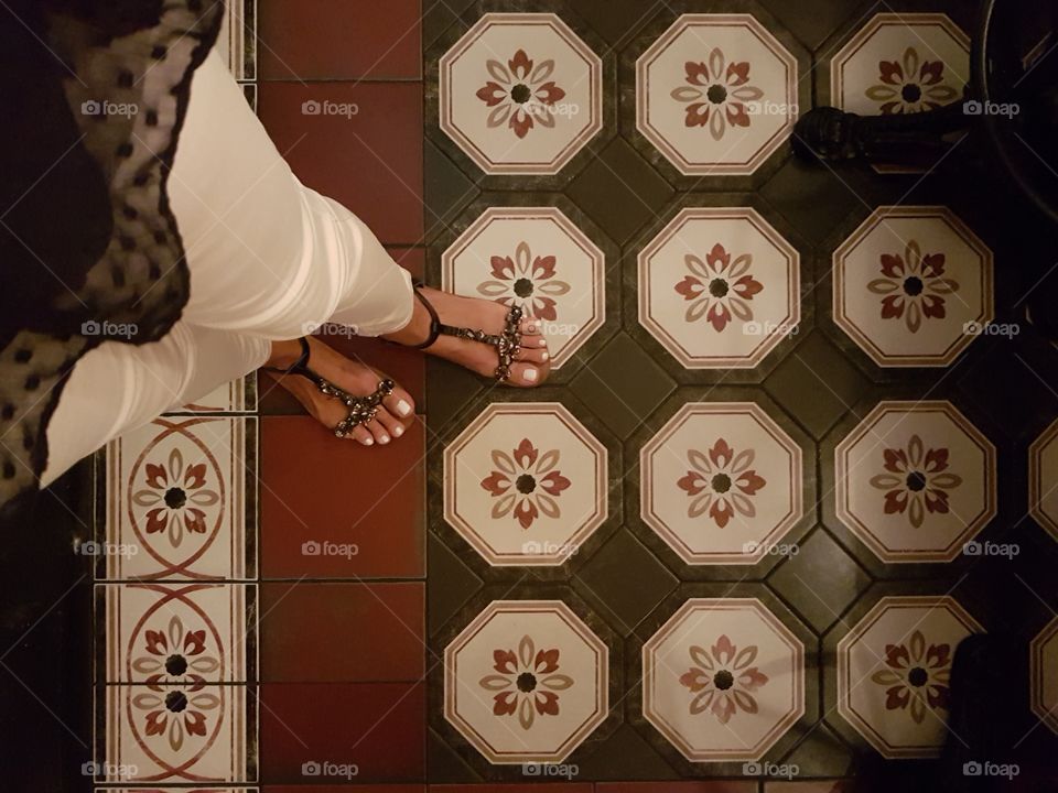 Woman legs and decorated tiles floor in red, black and white