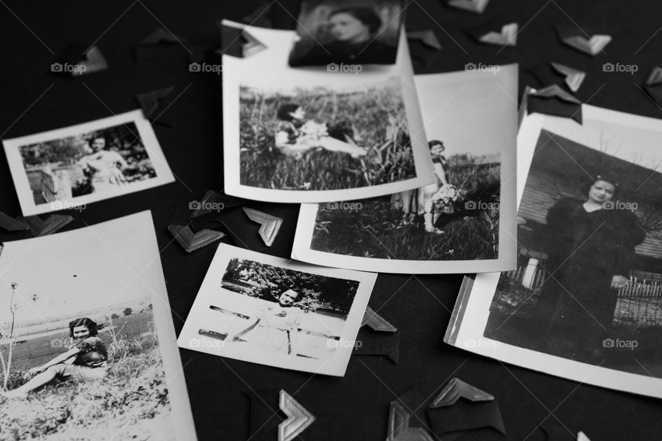 Collection of vintage photos and mounting corners on black surface in black and white