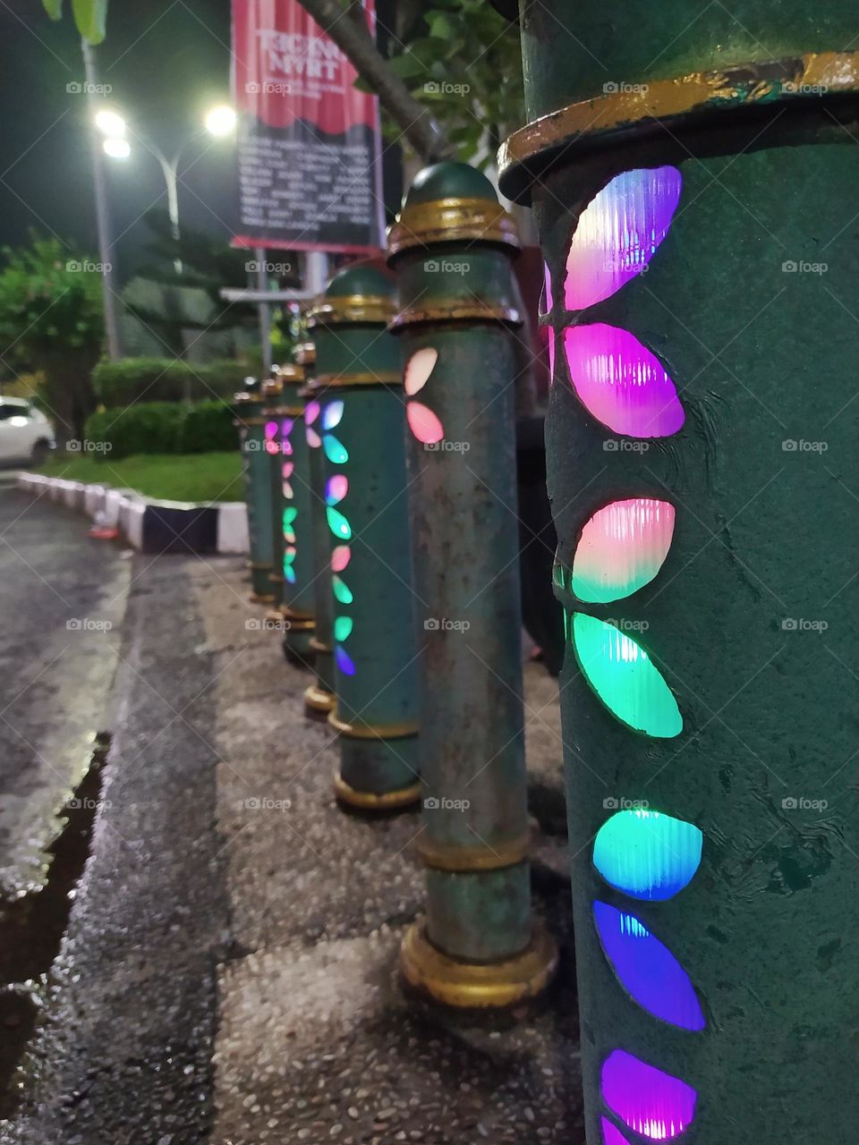 Short guardrail on the sidewalk with colorful lights at night