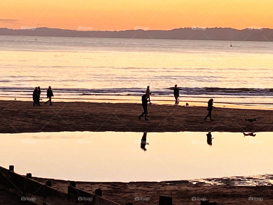 Late Autumn afternoon photo of last minute family fun on the beach, with a magnificent sunset to guide them.