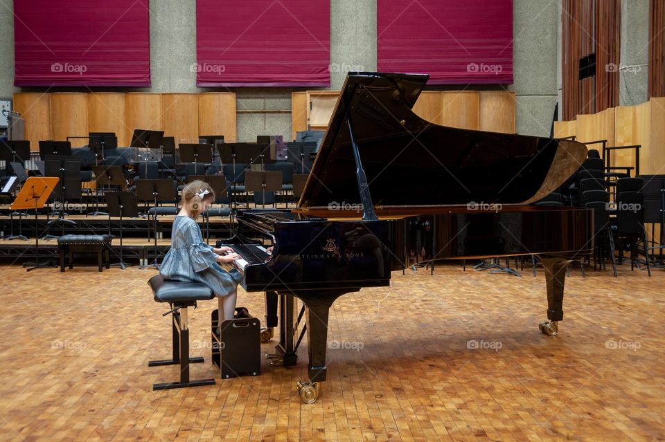 Little girl playing on grand piano.