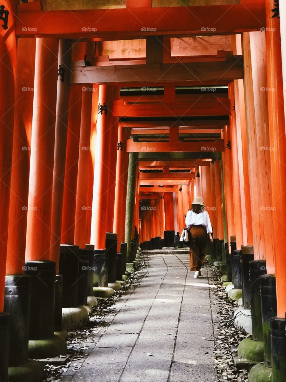 Mujer caminando entre los arcos rojos en Japón