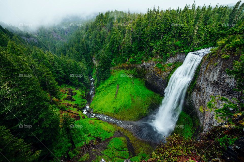 The waterfall in the mountains present s a beautiful natural landscape