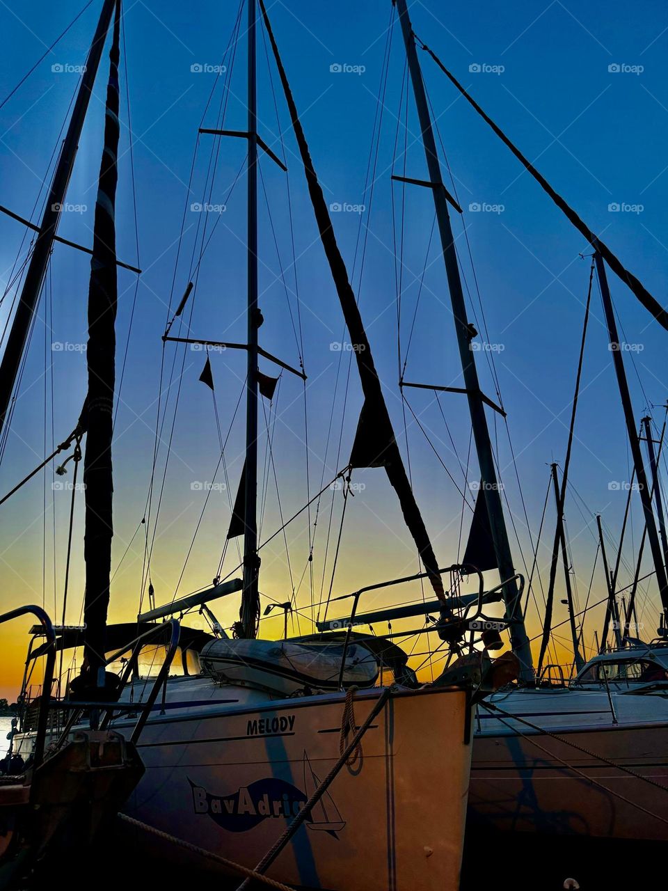 In the photo taken in the evening, white yachts sit quietly near the pier, illuminated by the soft light of the sunset.