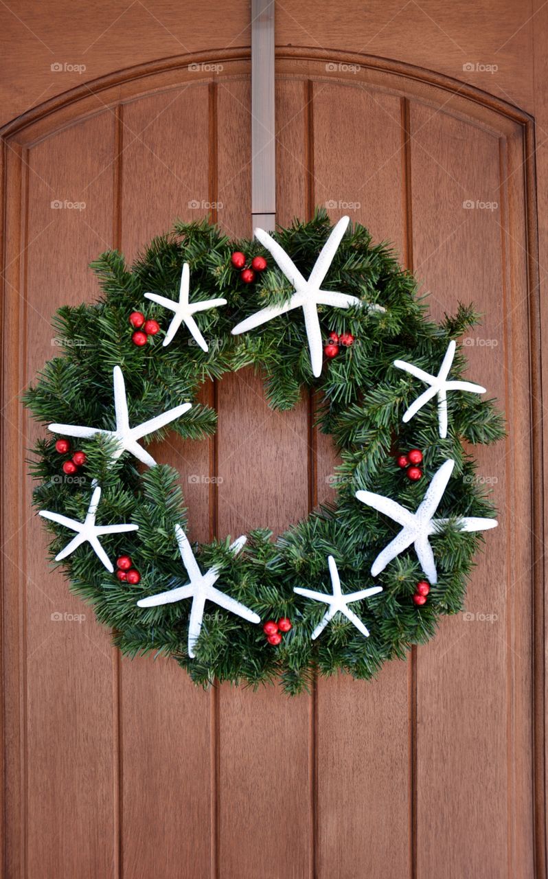 A costal themed wreath hanging on a wooden front door. 