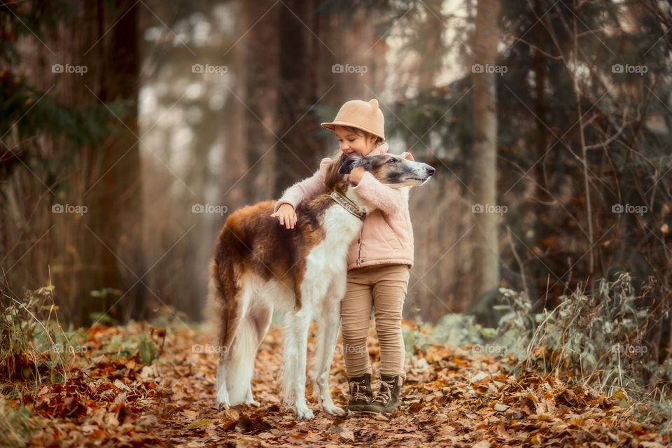 Cute smiling girl with borzoi dog in an autumn park 