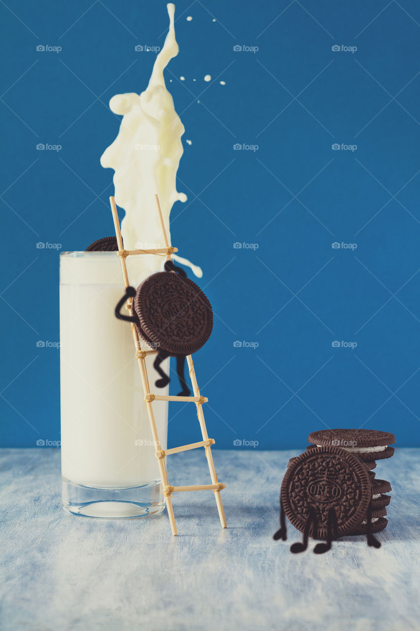 Oreo cookies and milk on blue background. Food art.
