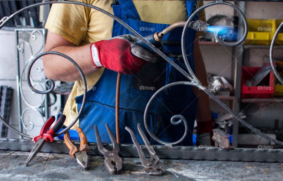 Craftsman heats iron with welding torch