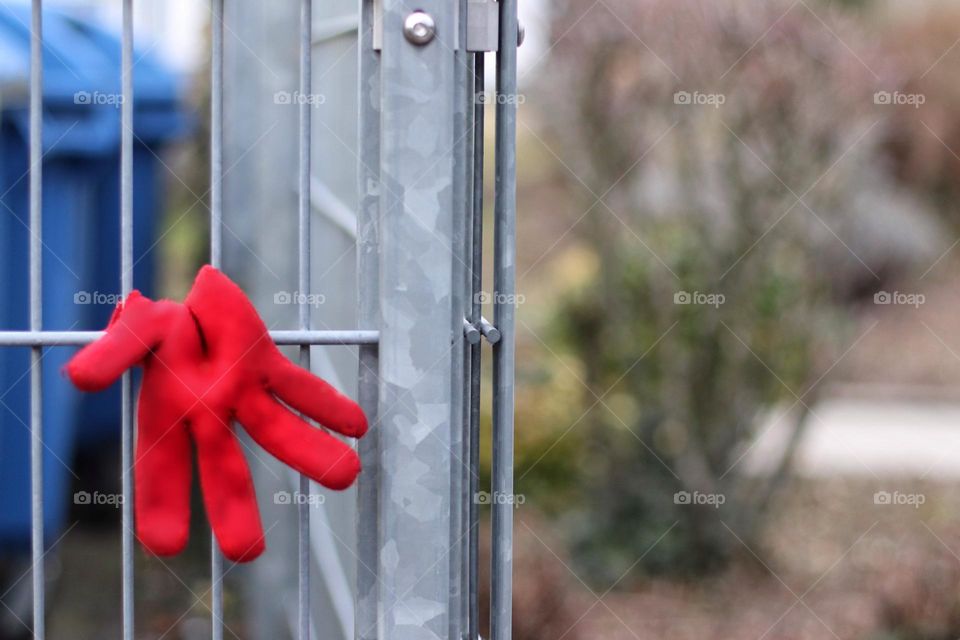 A red glove hangs over a metal fence