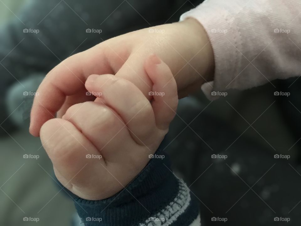 An infant and a toddler holding hands.