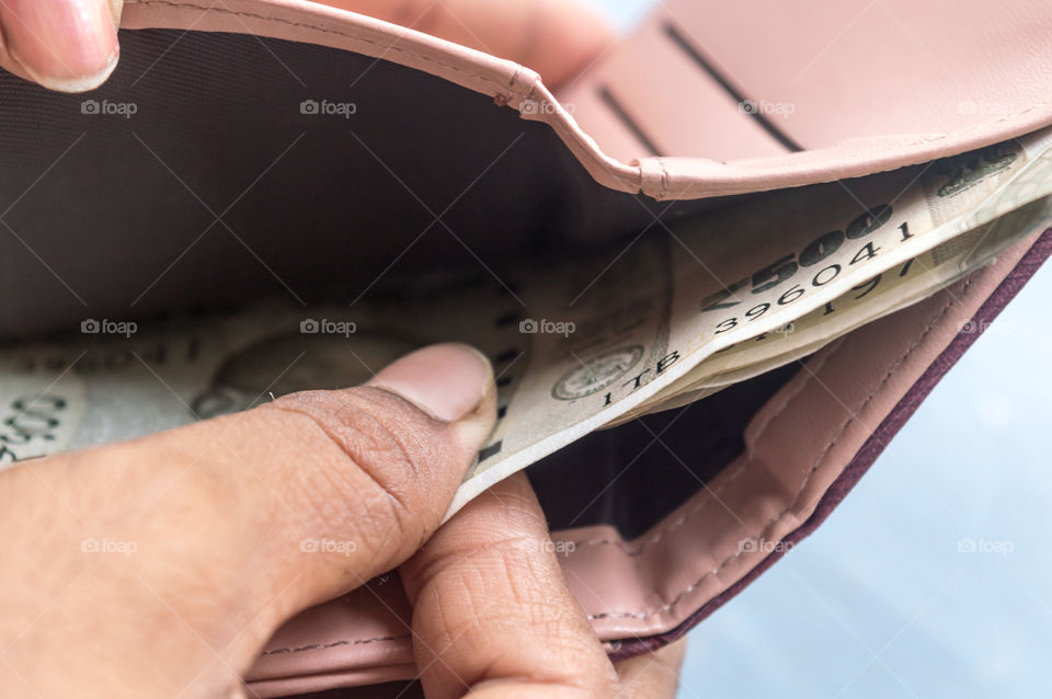 Businesswoman putting or taking out or paying Indian rupee banknotes from leather wallet. Isolated white background. Earning crisis growth bribe corruption bankrupt concept. Selective focus Close-up