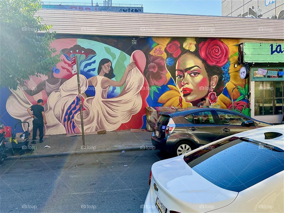 This beautiful art mural on “Jefferson St” off “Broadway” in “Bushwick”, Bklyn celebrates the Latin culture featuring dancing ladies pirouetting in long flowing white gowns. It extends over almost an entire city block. 2024. Hypnotic Productions