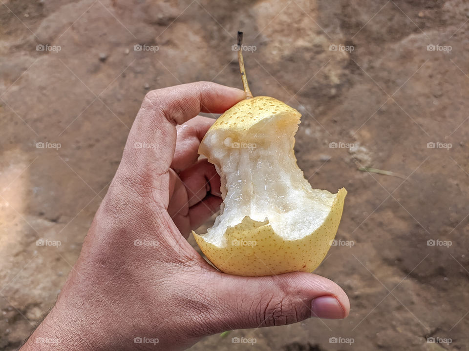 Close-up of hand holding pear with bite marks