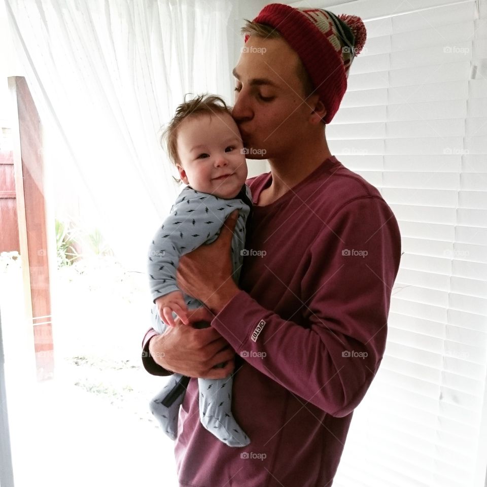 Young man holding baby and kissing