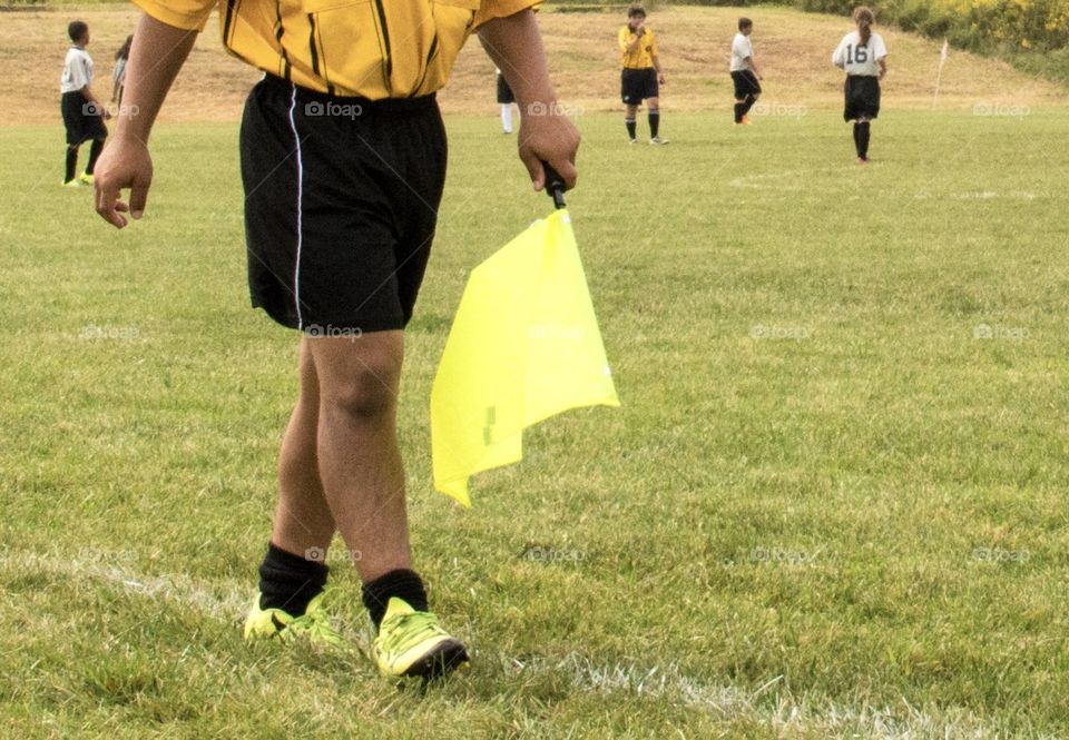 Waking, soccer official in bright yellow shoes with bright yellow flag