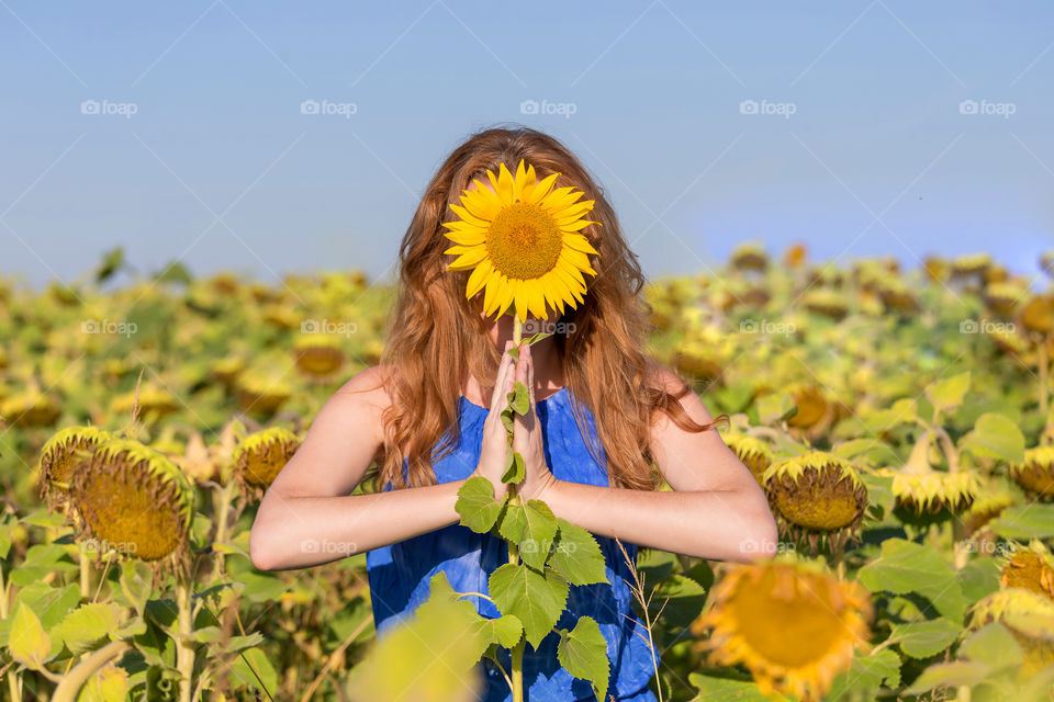 Girl in sunflower field making namaste pose