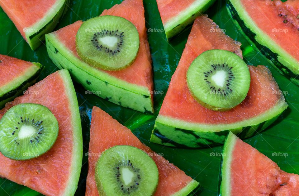 Kiwi and melon on a green leafy background 