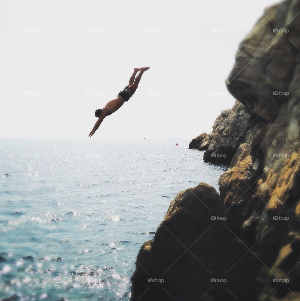 A man dives into the beautiful waters of the Adriatic off the coast of Dubrovnik, Croatia.
