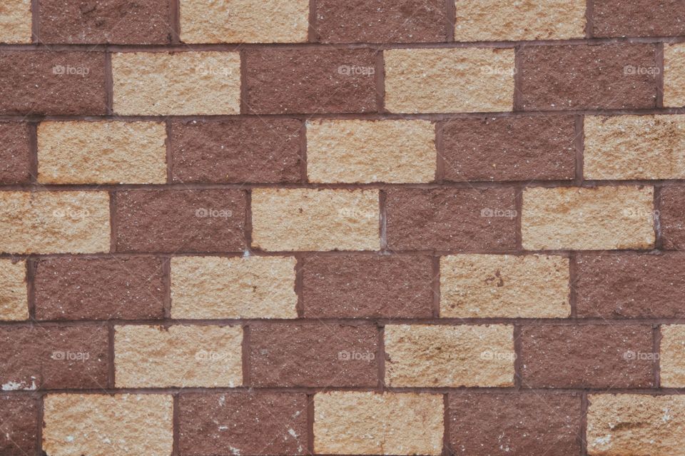 A pattern of brown and tan cement bricks on the facade of a building.