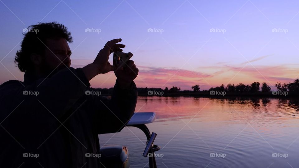 Silhouette of man shooting pics of sunset