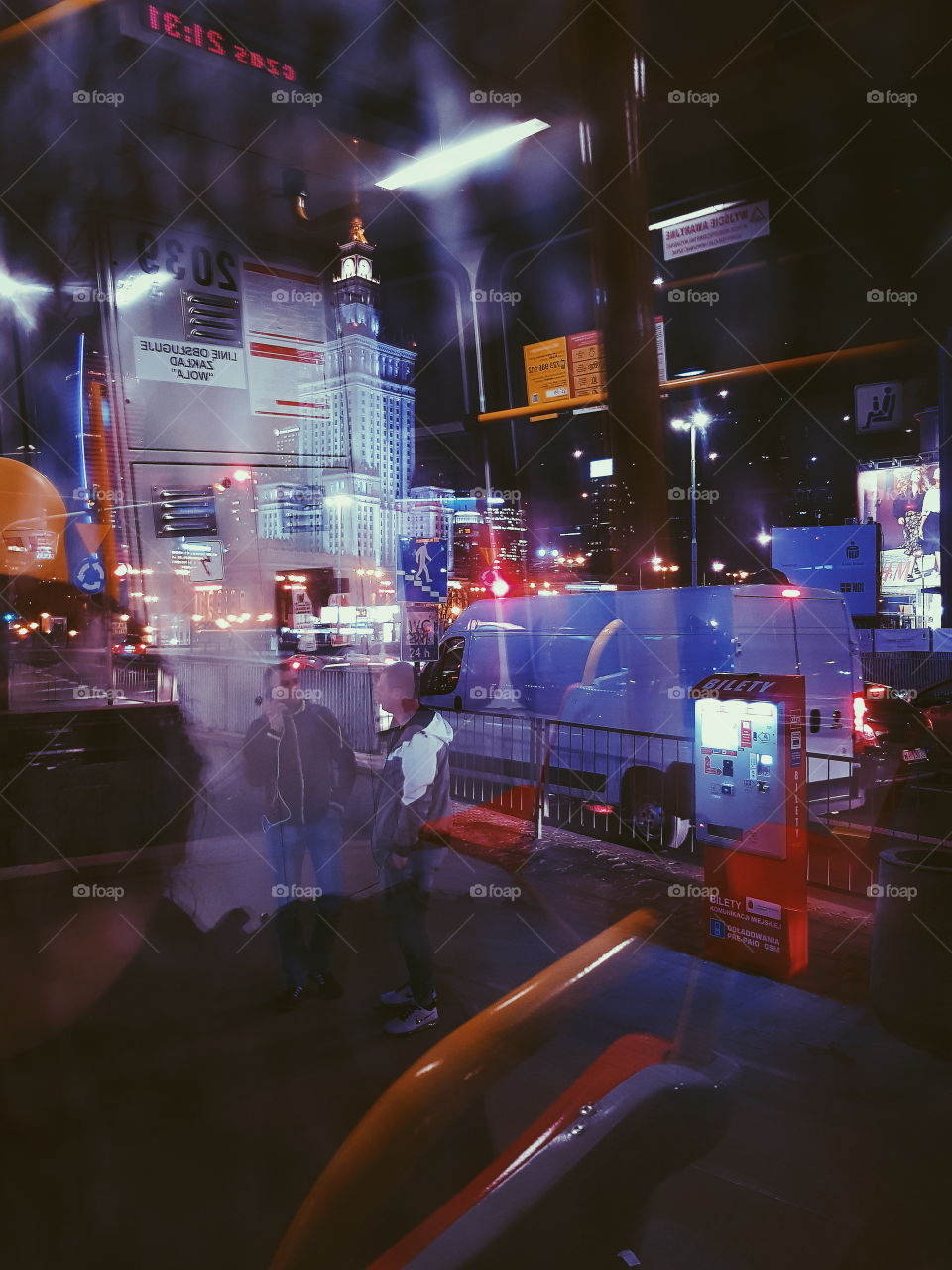 Reflection of the Interior of a tram at night with the city of Warsaw in the background. Purple neon colors.