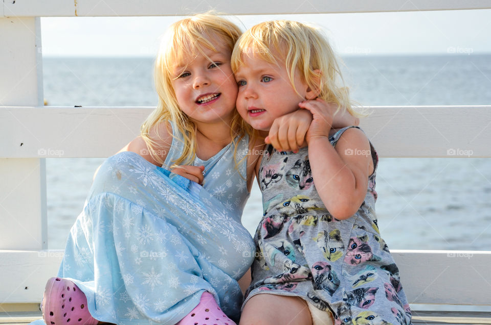 Happy sisters sitting on bench