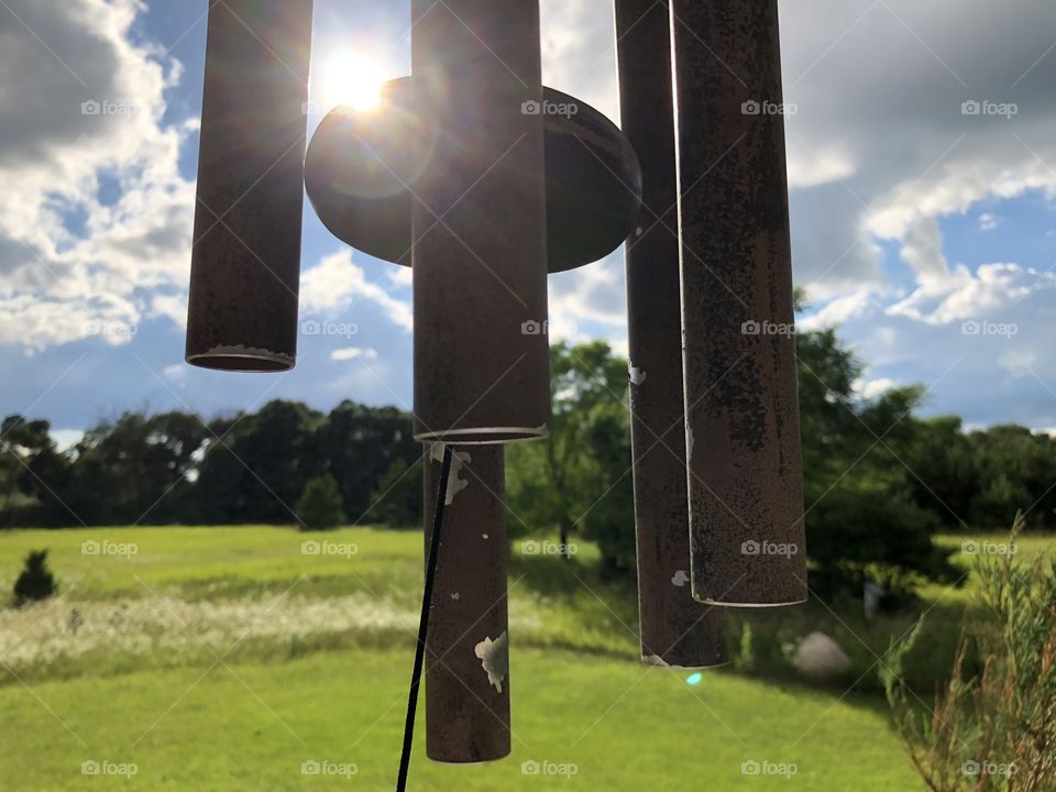 Rusty wind chimes before a cloudy blue sky
