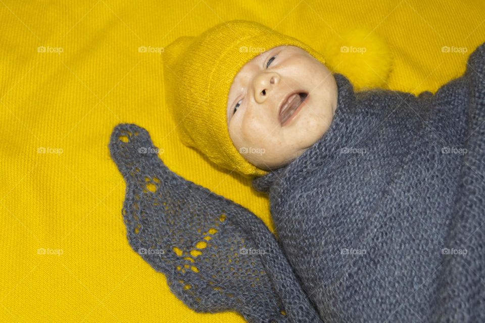A newborn baby on a yellow and gray background. A photo shoot in the style of Newborn and lifestyle.