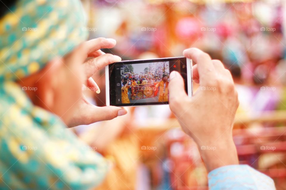 Photographers are using mobile phones to take pictures of colorful parades.  Exciting to tourists who have seen  He is trying to take the best picture out. Love photography.