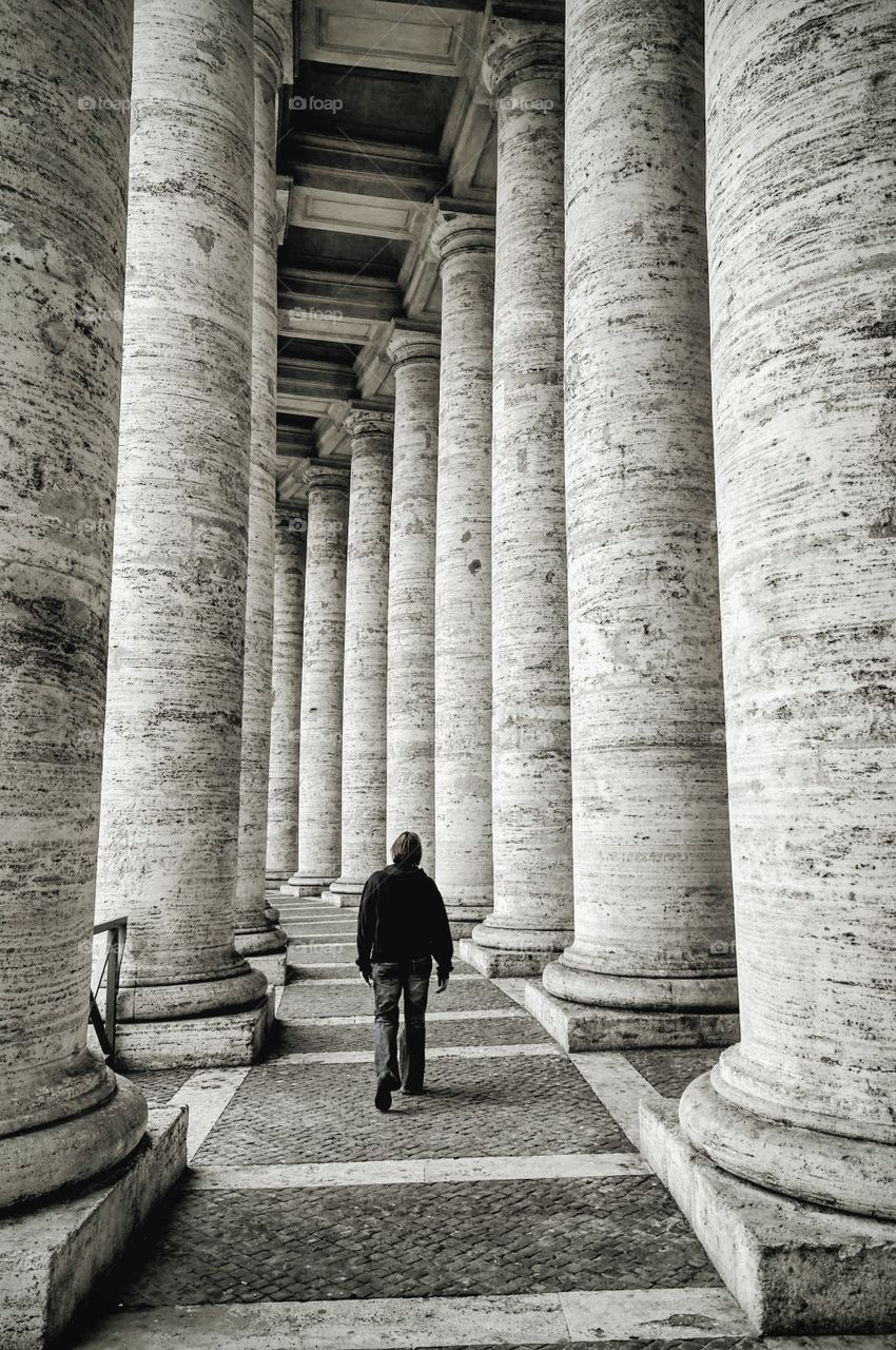 Rear view of man walking on the floor with pillars