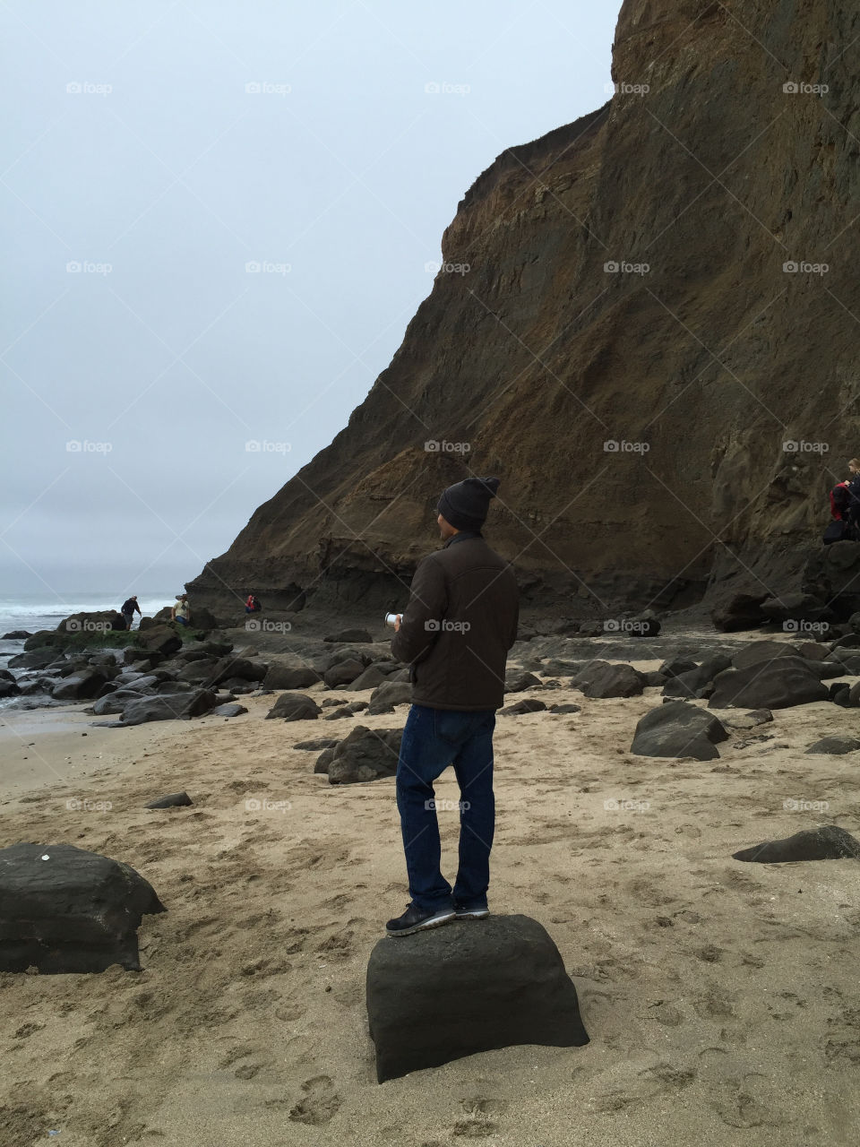 Man standing on a rock on the beach