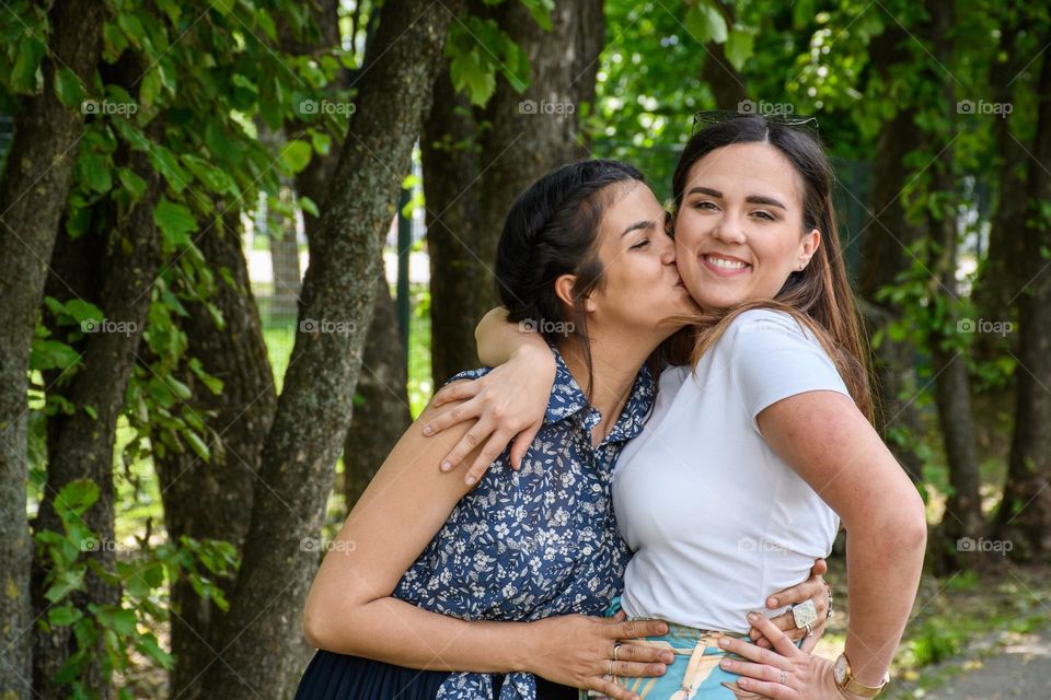 Two happy young woman hugging and kissing in park