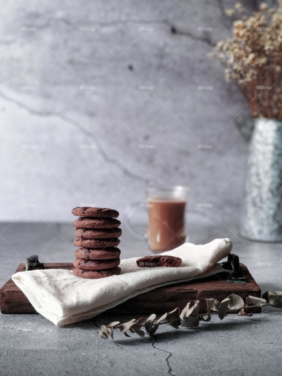 A stack of biscuits on wooden board and a cup of coffee at the back 