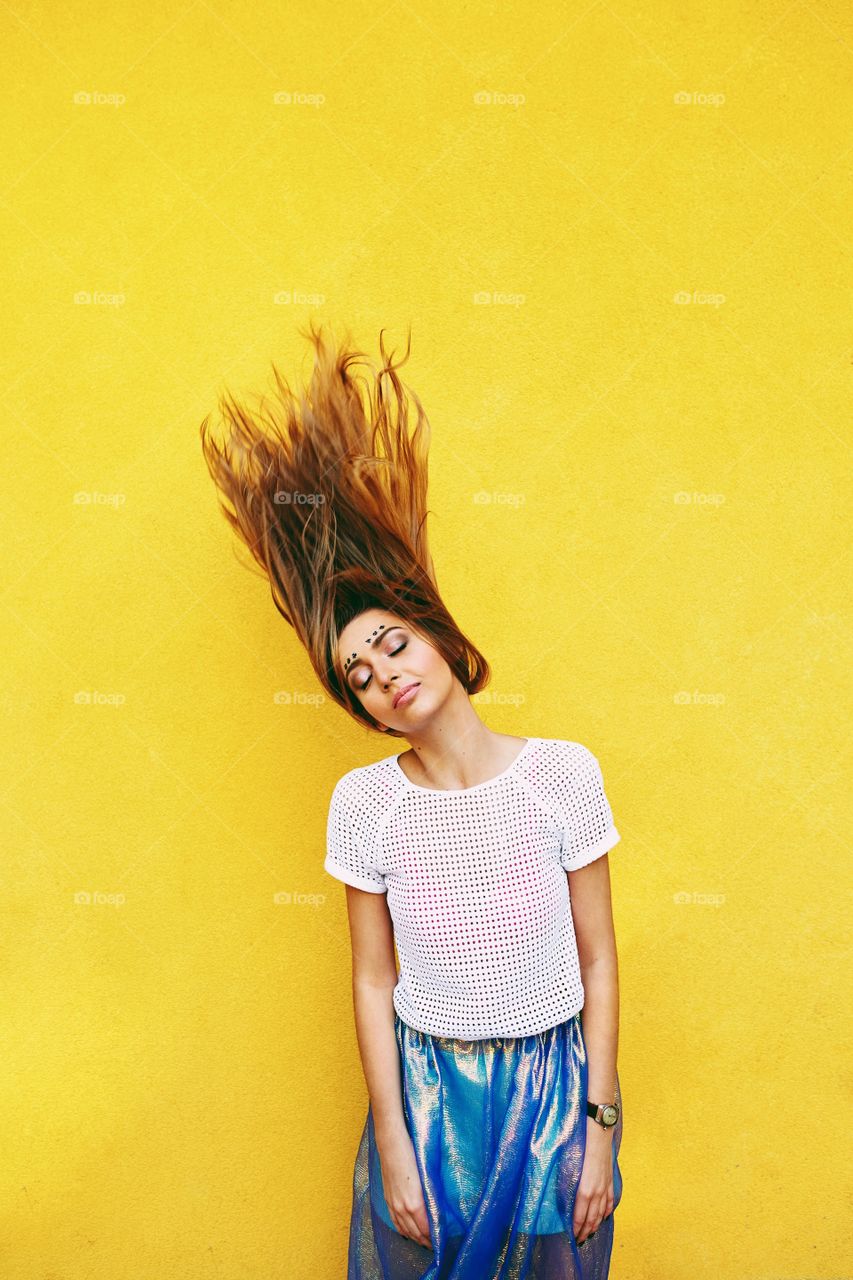 Yellow dreams . Attractive girl in an unusual skirt posing near a yellow wall