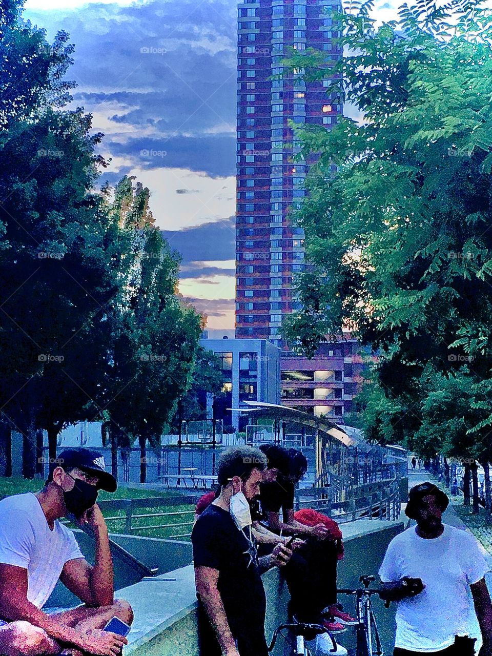 Pedestrians are walking by while others simply take in the scene at twilight time on “Vernon Jackson Avenue” and “48th Street” and yet others are waiting for their order from the Mexican taco stand. 2021. Hypnotic Productions