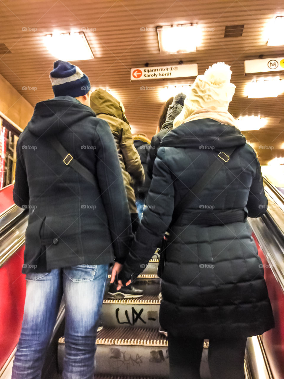 Couple In Love Holding Hands Standing On A Subway Escalator During Wintertime
