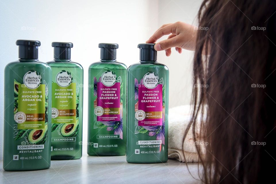 Woman with beautiful long healthy hair holding a bottle of Herbal Essences product